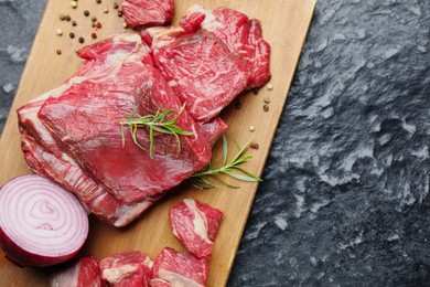 Photo of Pieces of raw beef meat and spices on black marble table, top view. Space for text
