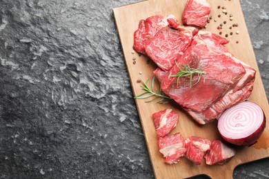 Photo of Pieces of raw beef meat and spices on black marble table, top view. Space for text
