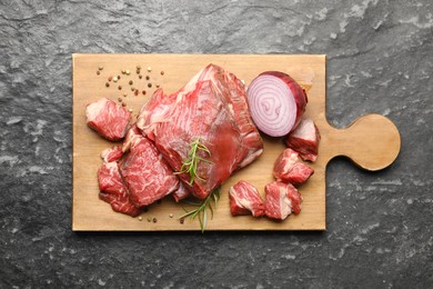 Photo of Pieces of raw beef meat and spices on black marble table, top view