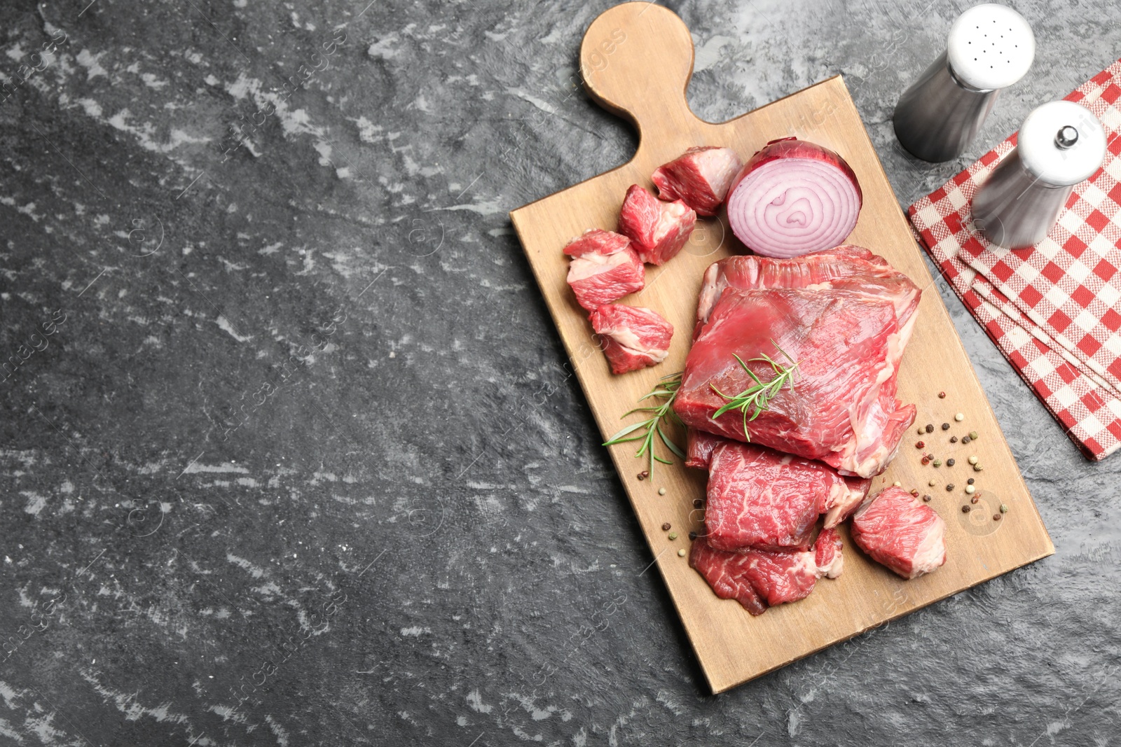 Photo of Pieces of raw beef meat and spices on black marble table, top view. Space for text