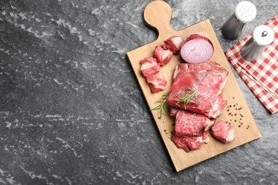 Photo of Pieces of raw beef meat and spices on black marble table, top view. Space for text