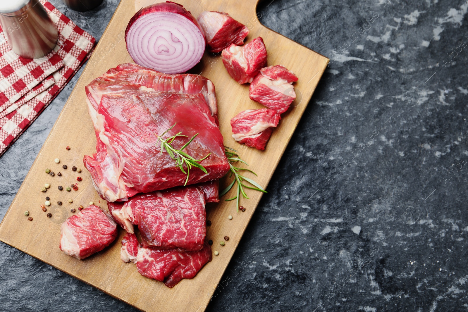 Pieces of raw beef meat and spices on black marble table, top view. Space for text Photo of Pieces of raw beef meat and spices on black marble table, top view. Space for text