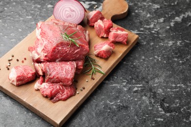Photo of Pieces of raw beef meat and spices on black marble table, closeup. Space for text