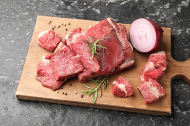 Photo of Pieces of raw beef meat and spices on black marble table, above view
