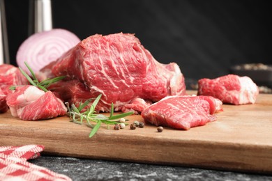 Photo of Pieces of raw beef meat and spices on black marble table, closeup