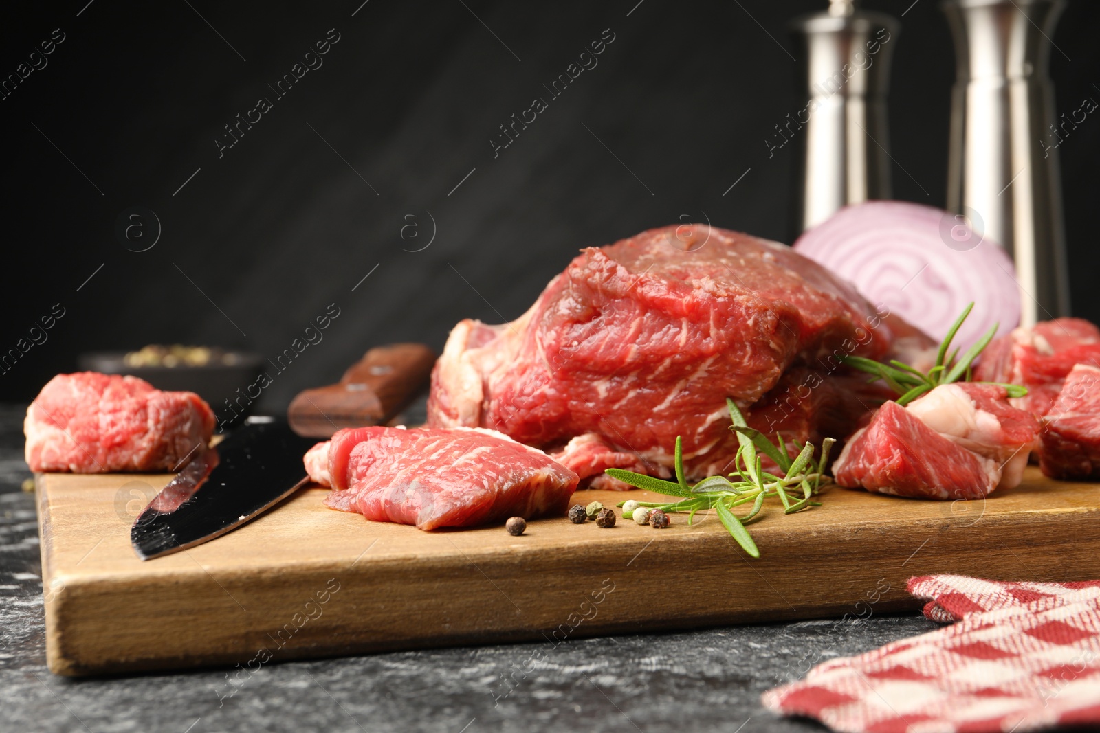 Pieces of raw beef meat, spices and knife on black marble table, closeup Photo of Pieces of raw beef meat, spices and knife on black marble table, closeup