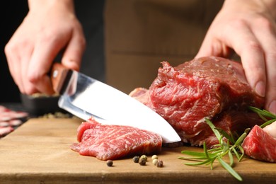 Photo of Woman cutting raw beef meat at table, closeup