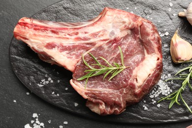 Photo of Piece of raw beef meat and spices on black table, top view