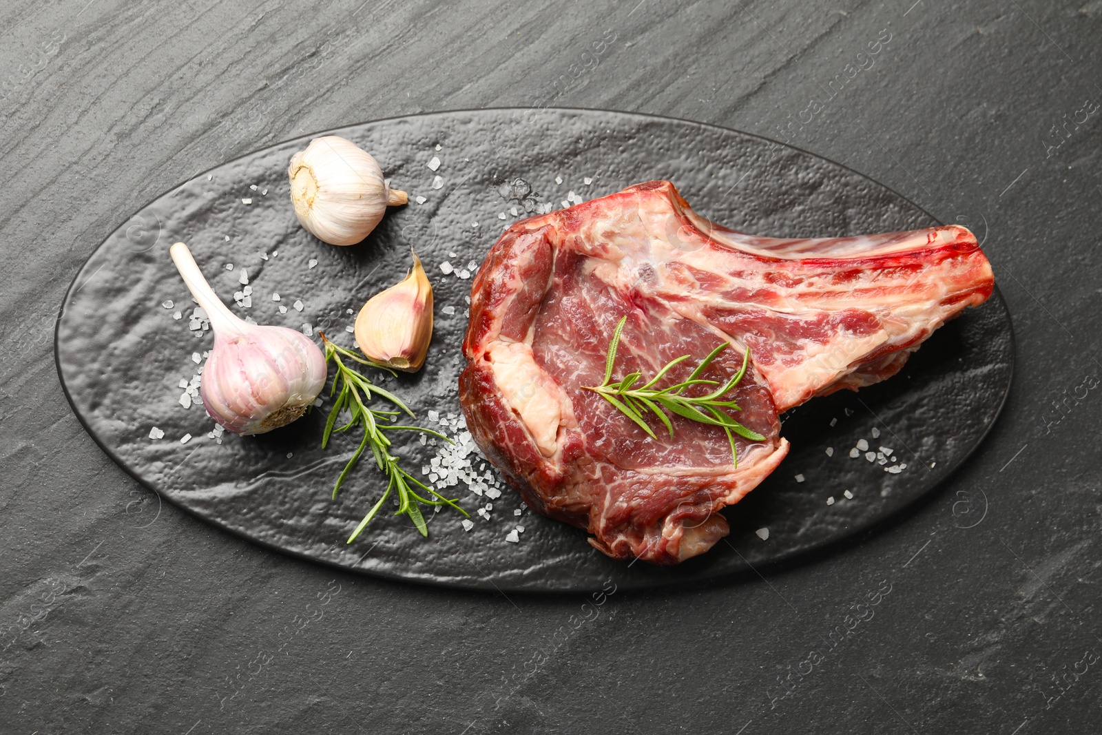 Photo of Piece of raw beef meat and spices on black table, top view