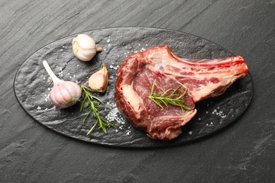 Photo of Piece of raw beef meat and spices on black table, top view