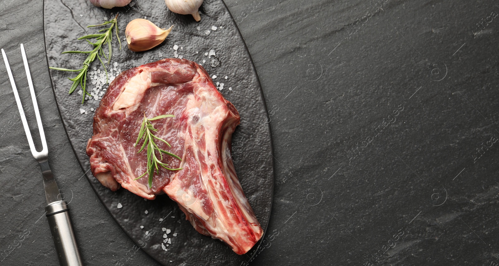 Piece of raw beef meat, spices and carving fork on black table, flat lay. Space for text Photo of Piece of raw beef meat, spices and carving fork on black table, flat lay. Space for text
