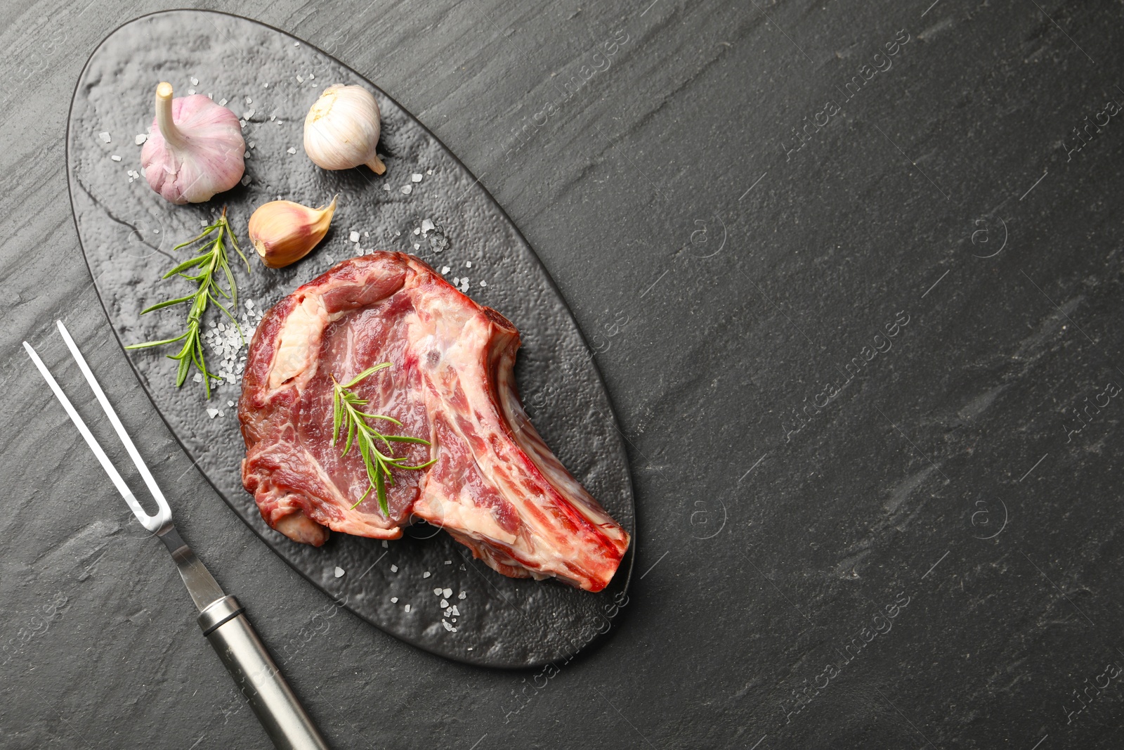 Piece of raw beef meat, spices and carving fork on black table, flat lay. Space for text Photo of Piece of raw beef meat, spices and carving fork on black table, flat lay. Space for text