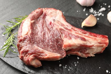 Photo of Piece of raw beef meat and spices on black table, closeup