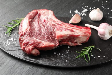 Photo of Piece of raw beef meat and spices on black table, closeup