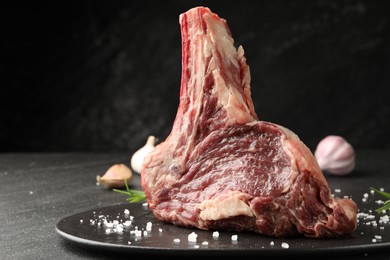 Photo of Piece of raw beef meat and spices on black table, closeup. Space for text