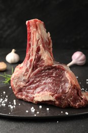 Photo of Piece of raw beef meat and spices on black table, closeup