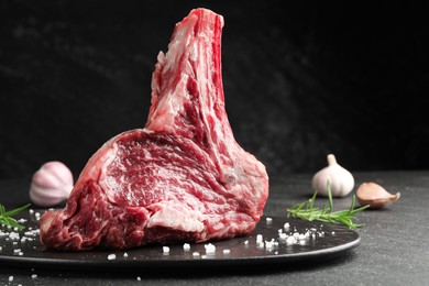 Photo of Piece of raw beef meat and spices on black table, closeup. Space for text