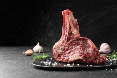 Photo of Piece of raw beef meat and spices on black table, closeup. Space for text