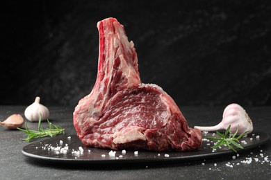 Photo of Piece of raw beef meat and spices on black table, closeup