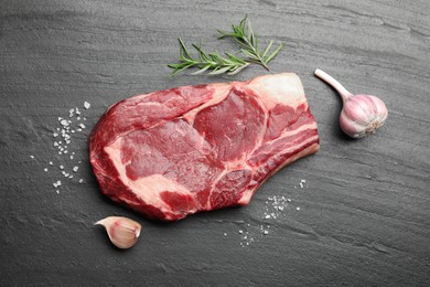 Photo of Piece of raw beef meat and spices on black table, flat lay