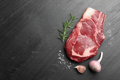 Photo of Piece of raw beef meat and spices on black table, flat lay. Space for text
