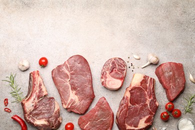 Photo of Pieces of raw beef meat, spices and tomatoes on grey table, flat lay. Space for text