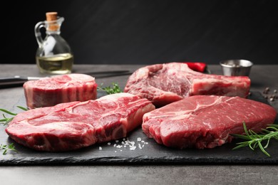 Photo of Pieces of raw beef meat and spices on grey table, closeup