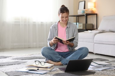 Photo of Smiling student with laptop and books preparing for exam on floor indoors. Space for text