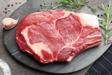 Photo of Piece of raw beef meat and spices on grey table, top view
