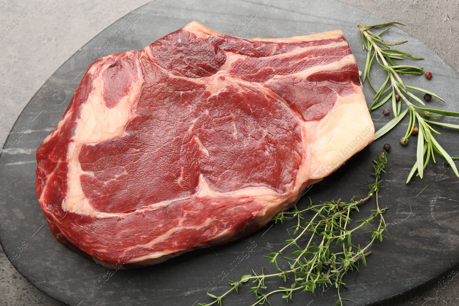 Piece of raw beef meat and spices on grey table, top view Photo of Piece of raw beef meat and spices on grey table, top view
