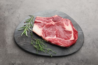 Photo of Piece of raw beef meat and spices on grey table, top view