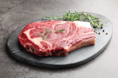 Photo of Piece of raw beef meat and spices on grey table, closeup