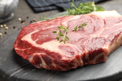 Photo of Piece of raw beef meat and spices on grey table, closeup