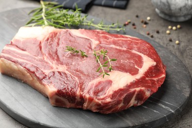 Photo of Piece of raw beef meat and spices on grey table, closeup