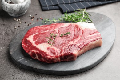 Photo of Piece of raw beef meat and spices on grey table, closeup