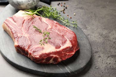 Photo of Piece of raw beef meat and spices on grey table, closeup. Space for text