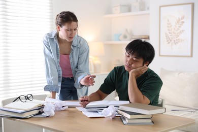 Photo of Tired students with books preparing for exam at wooden table indoors