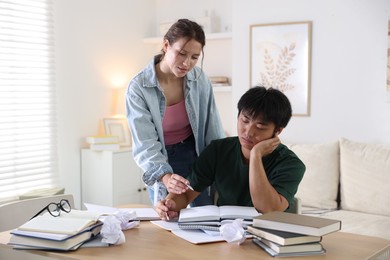 Photo of Students with books preparing for exam at table indoors