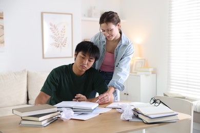 Photo of Students with books preparing for exam at table indoors