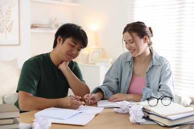 Photo of Happy students with books preparing for exam at table indoors