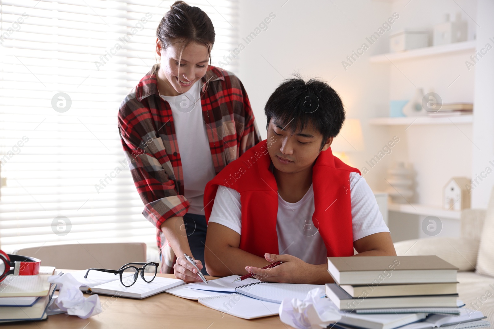 Photo of Students with books preparing for exam at table indoors