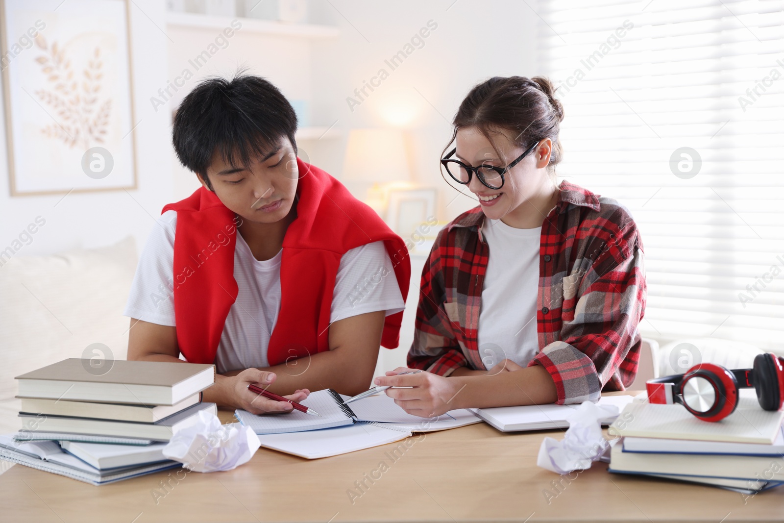 Photo of Students with books preparing for exam at table indoors