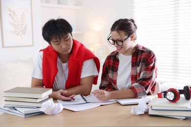 Photo of Students with books preparing for exam at table indoors