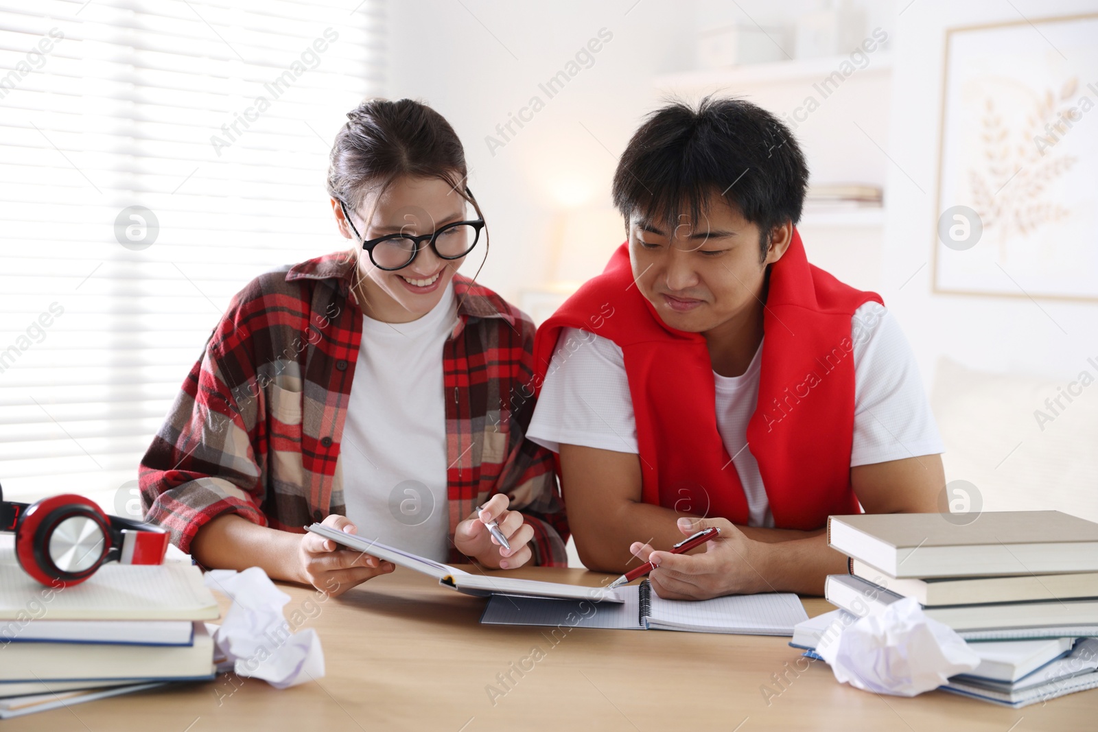 Photo of Students with books preparing for exam at table indoors