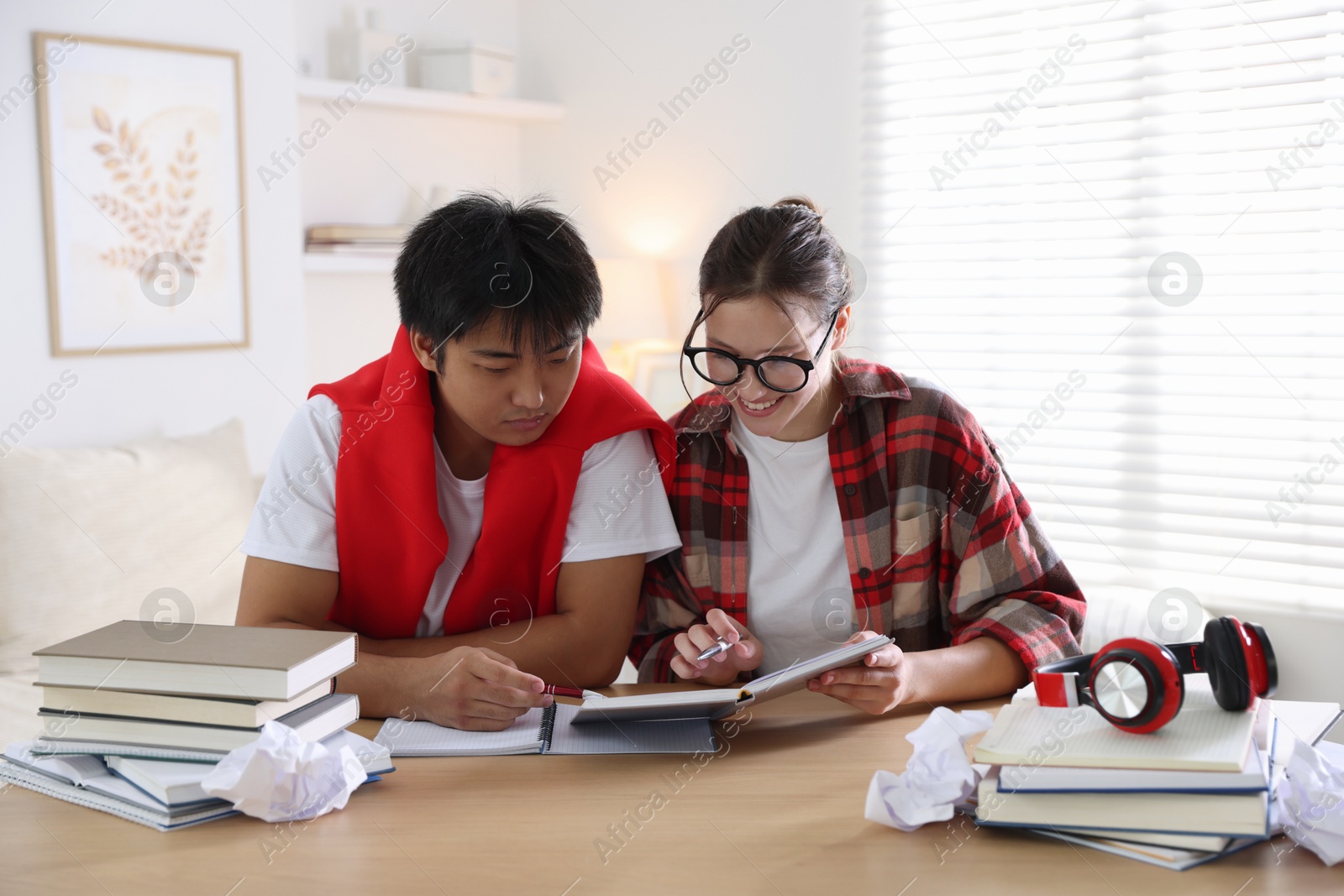 Photo of Students with books preparing for exam at wooden table indoors