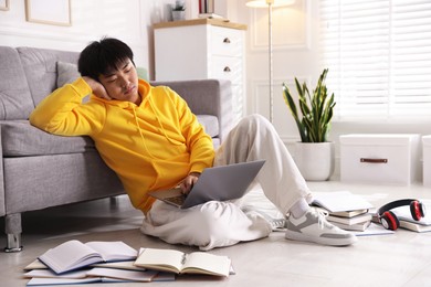 Photo of Student with laptop and books preparing for exam on floor at home