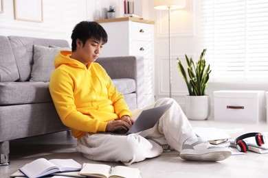 Photo of Student with laptop and books preparing for exam on floor at home