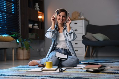 Photo of Happy student in headphones preparing for exam on floor at home