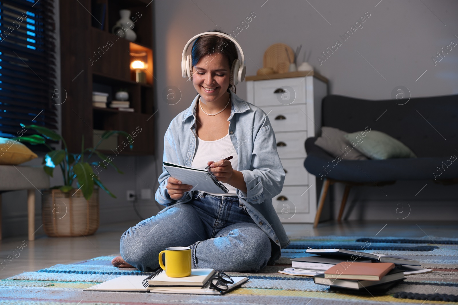 Photo of Happy student in headphones preparing for exam on floor at home
