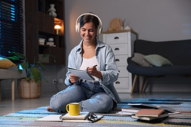 Photo of Happy student in headphones preparing for exam on floor at home